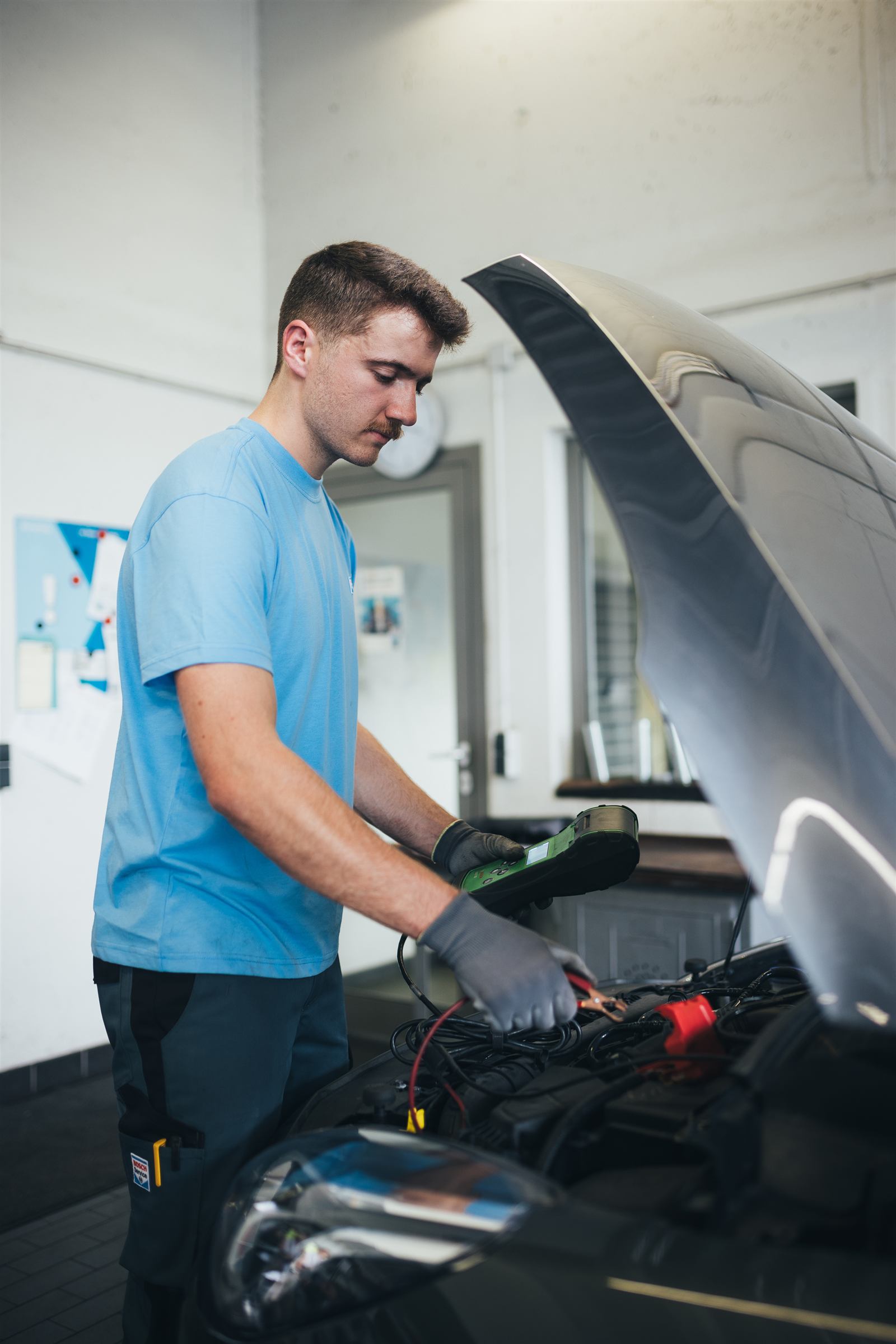 Tècnic revisant la bateria d'un vehicle amb equip de diagnosi Bosch